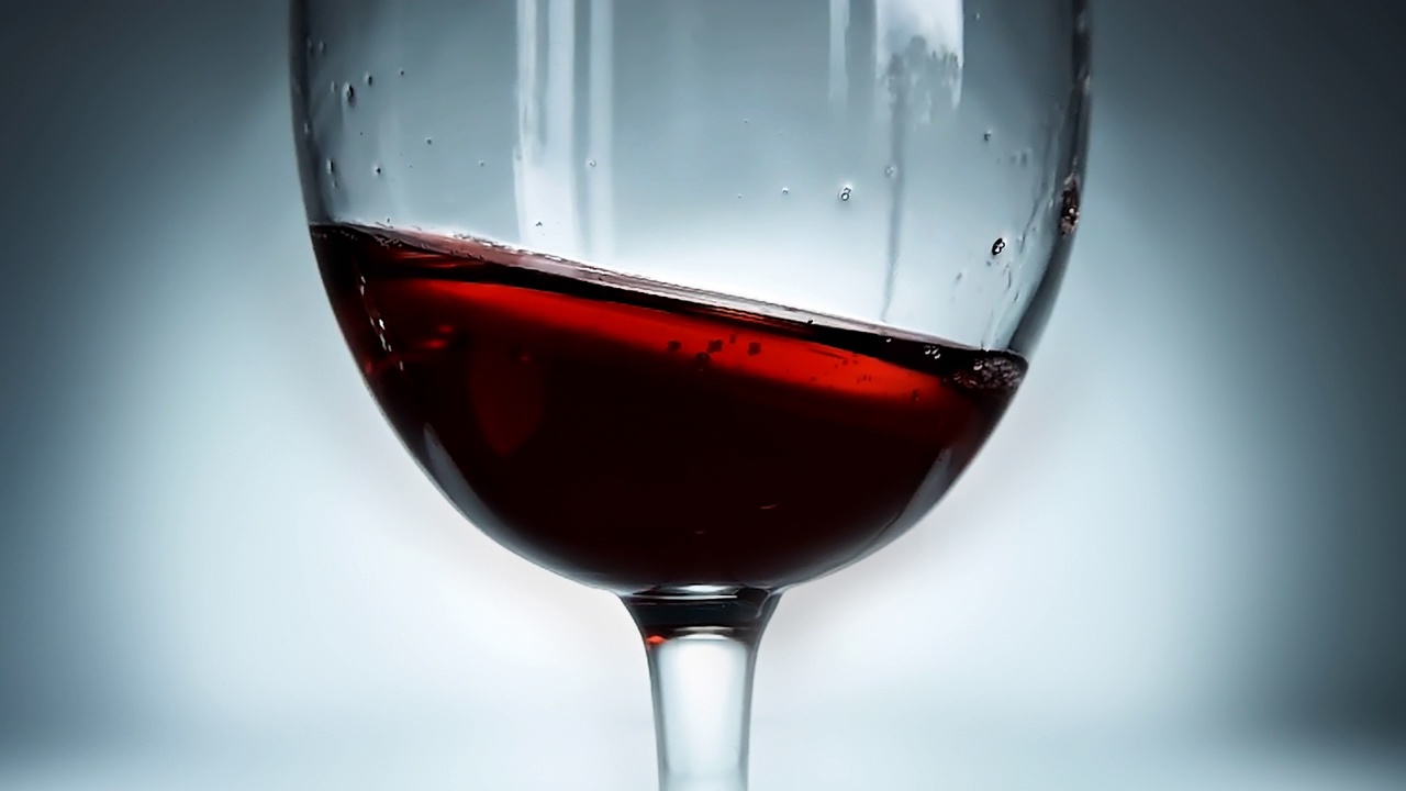 创意微距慢动作4k视频，红酒从一边到另一边溅在杯子里，像波浪一样。酒杯溅酒特写。视频素材