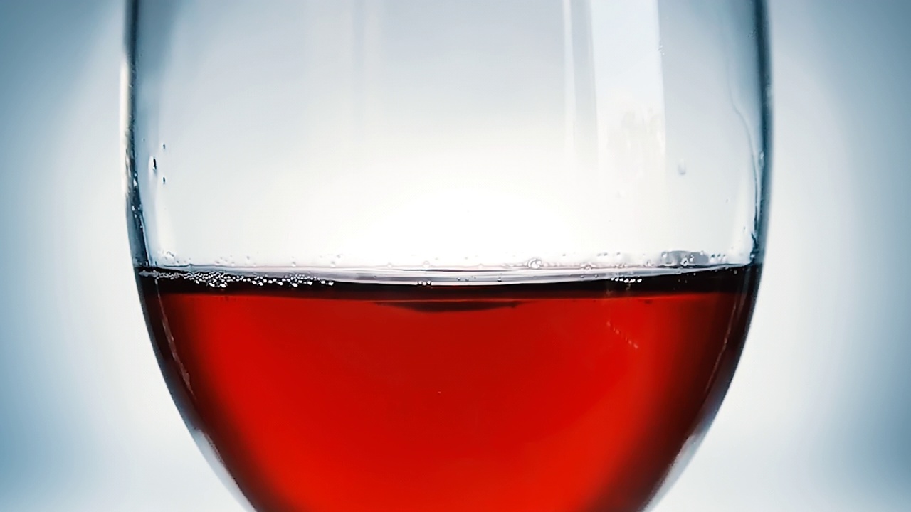 创意微距慢动作4k视频红酒在一个杯子和一滴葡萄酒。一杯缓缓落下的酒的特写镜头。视频素材