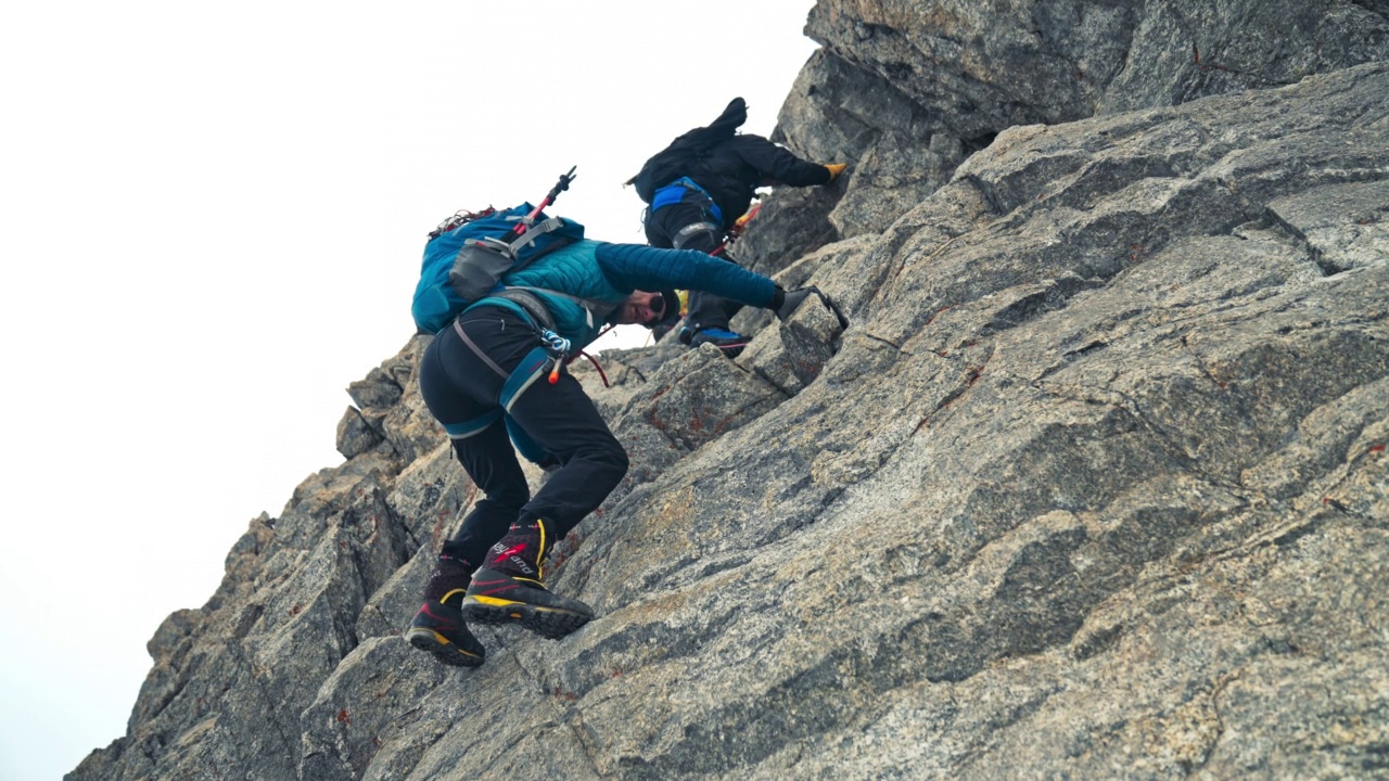 一队登山者正在攀登欧洲阿尔卑斯山的陡峭山峰。使用绳索和攀爬设备视频下载