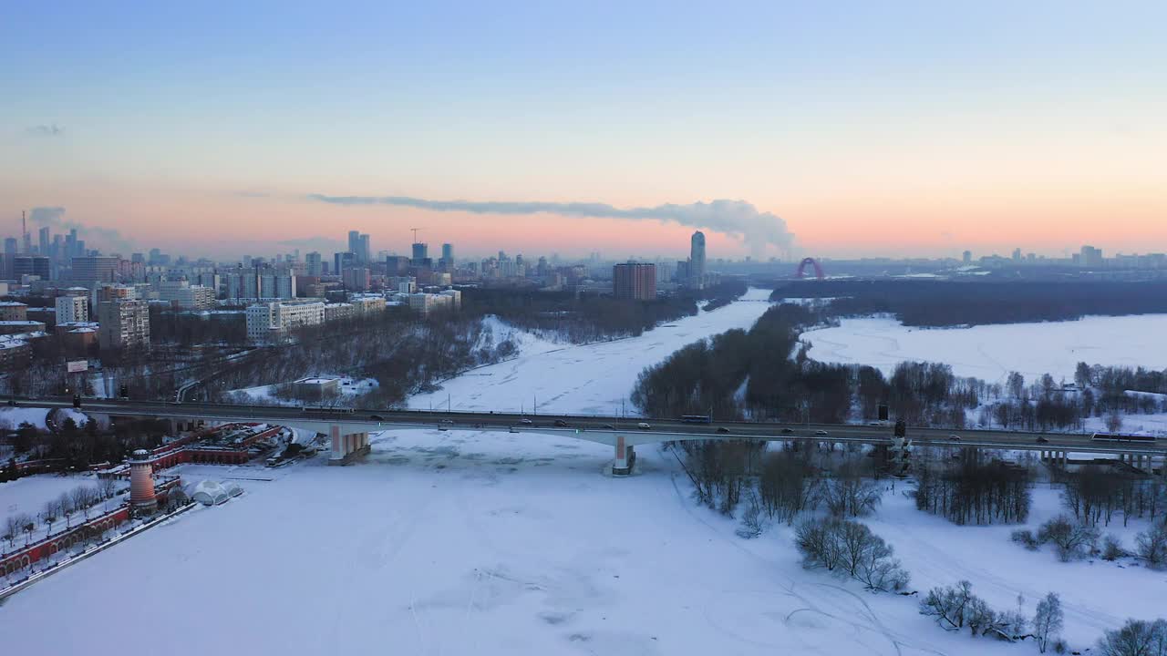 冬季黄昏拂晓，无人机在城市结冰的河和桥上飞行视频素材