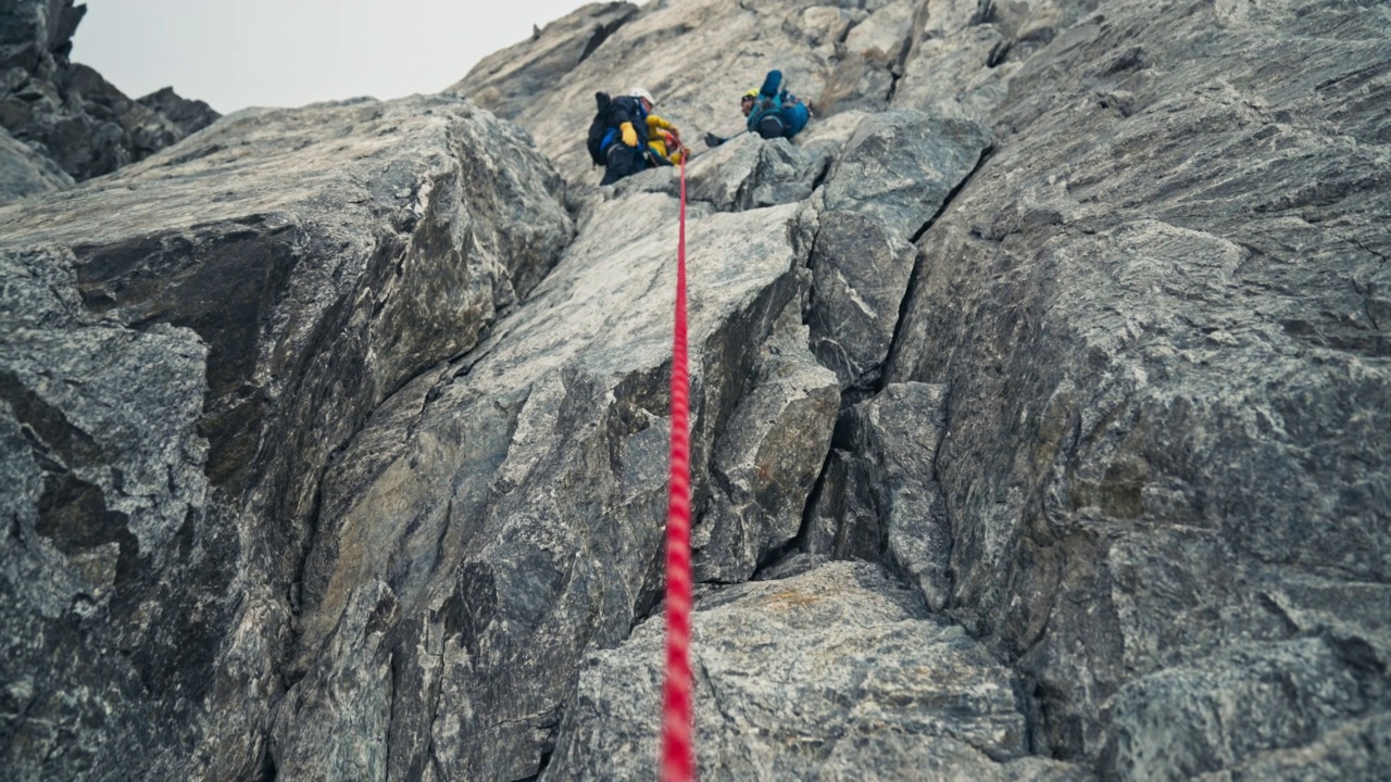 专业登山者攀登欧洲阿尔卑斯山的陡峭山峰。使用绳子。查找视频下载