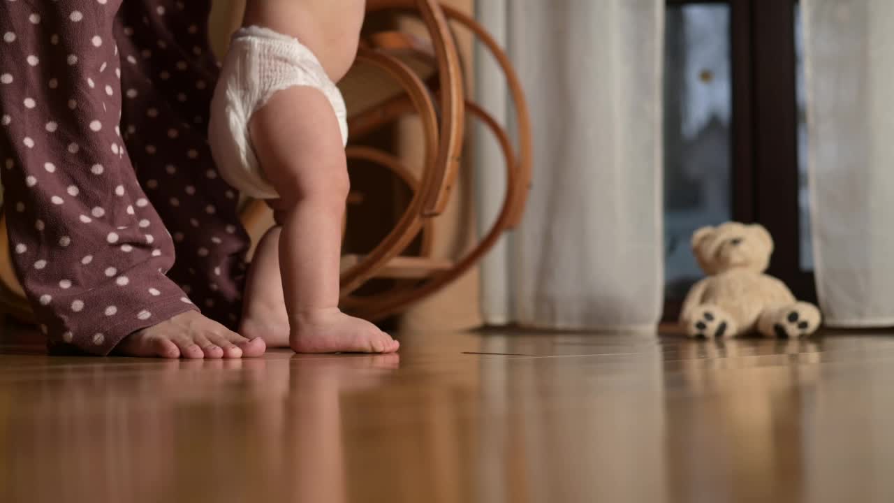 一个小男孩在屋子里迈出的第一步。穿尿布的婴儿学走路视频素材