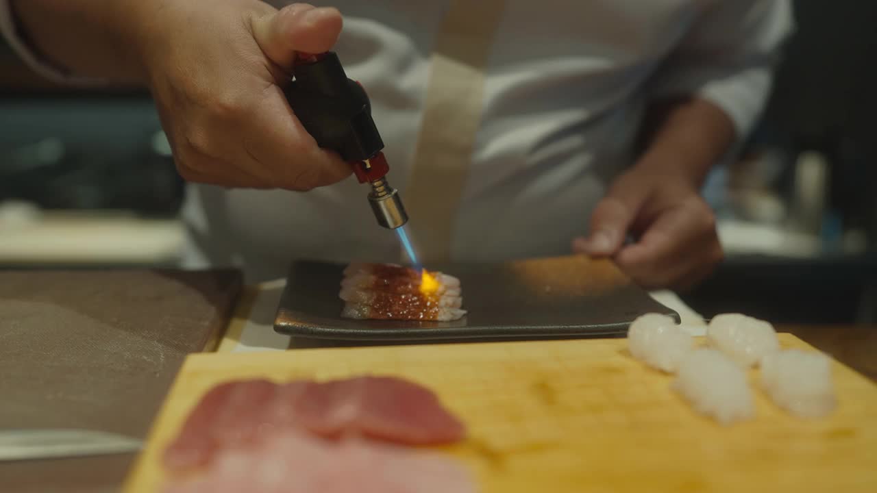 近距离的日本寿司厨师的手使用火炬燃烧金枪鱼寿司的客户omakase课程视频下载