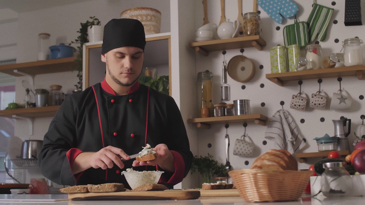 复制空间拍摄的厨师涂抹奶油芝士与韭菜混合黑麦面包片视频下载