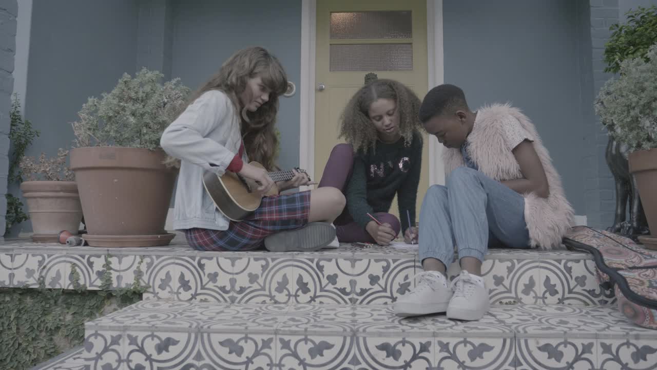 女孩在弹吉他，而女性朋友在书上涂色视频下载