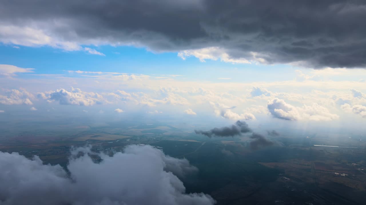 从高空的飞机窗口鸟瞰，远处的城市被暴雨前形成的蓬松的积云所覆盖视频下载