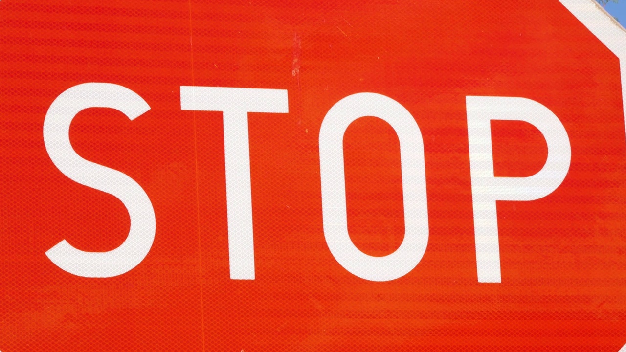 简单的红色停止路标，停止文本符号细节，宏观，极端特写，没有人。停车、停止行动、交通管制、法律禁止、警告标志抽象概念、交通运输视频素材