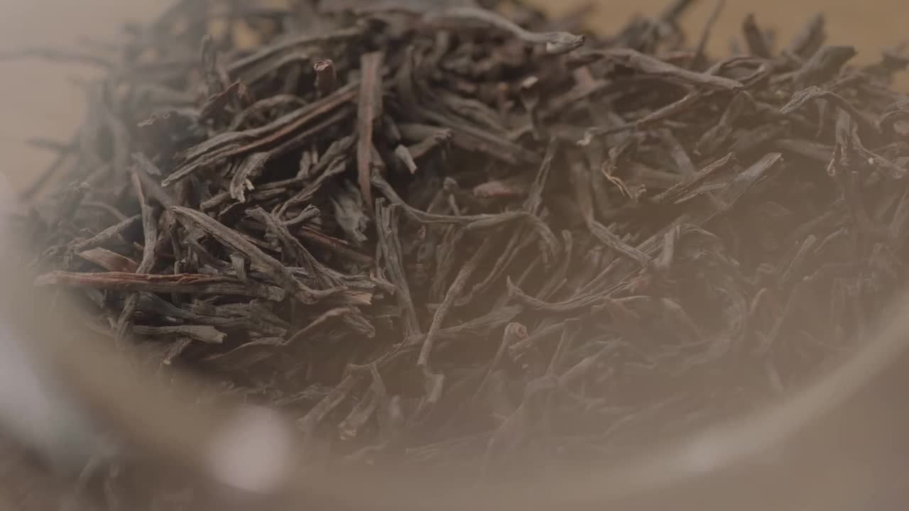 慢镜头，红茶的叶子正在掉进茶壶里。视频下载