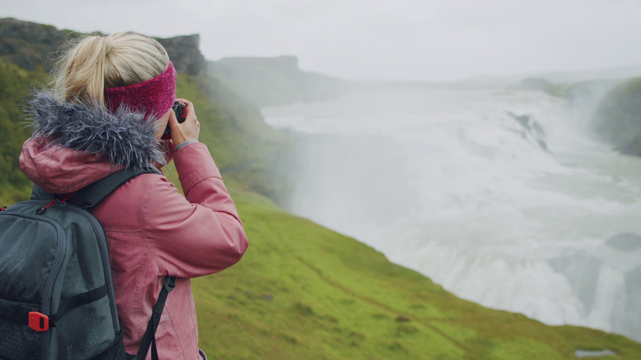 女游客在雨中拍摄令人印象深刻的Gullfoss瀑布。著名的景点和地标性的目的地在冰岛的黄金圈视频下载