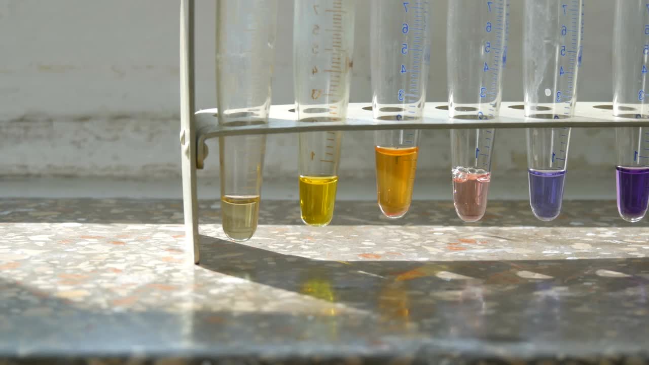 彩色液态水在医学试管在实验室的旧窗户与大理石窗台。视频下载