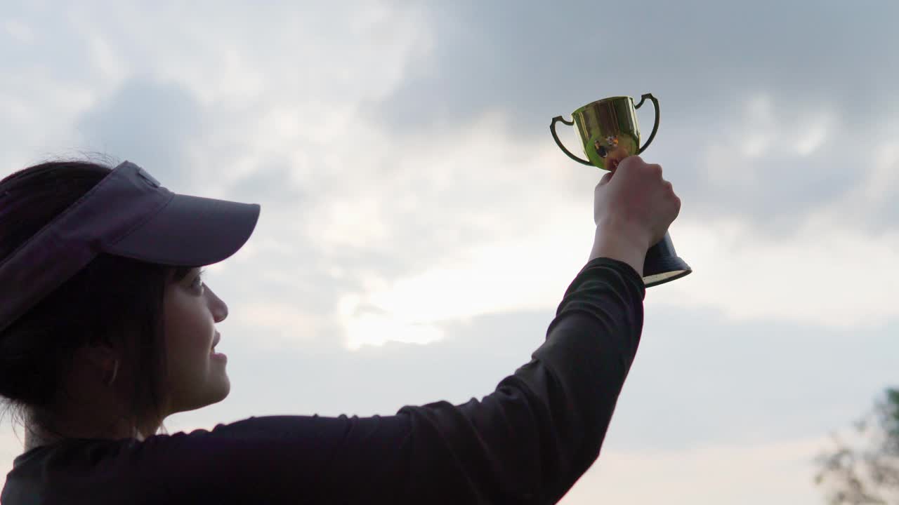 胜利者在高尔夫球场上手持奖杯视频素材