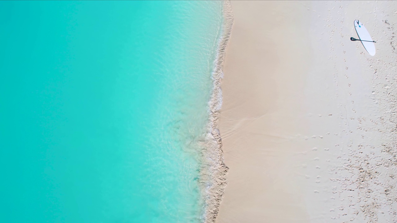 从空中俯瞰，一个男人在热带海滩跑进蓝绿色的大海视频下载