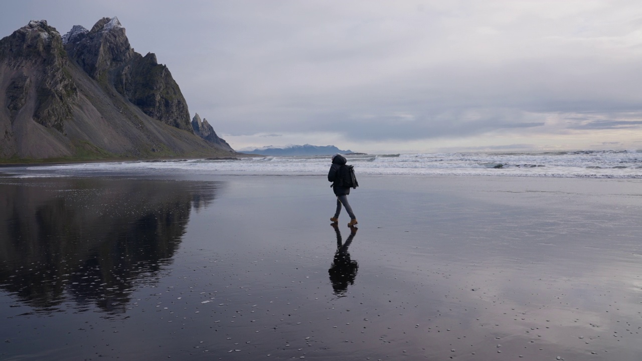 背着背包的男人沿着潮湿的海滩走向维斯特拉霍恩视频下载