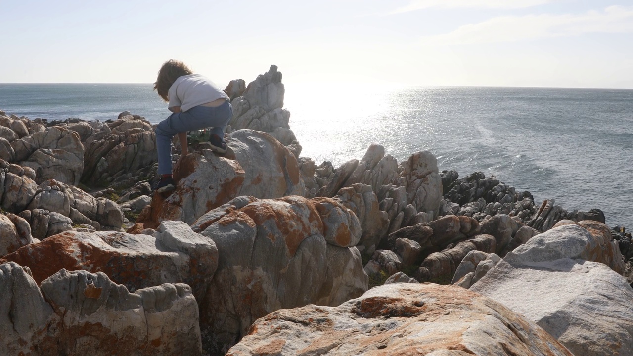 小男孩探索岩石海岸，岩石，德科德斯，南非视频素材