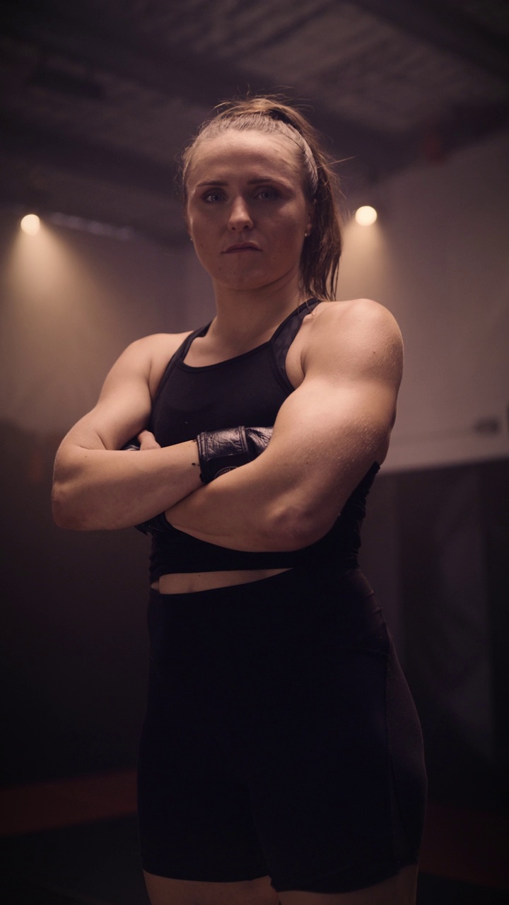 高端垂直移动视频慢动作肖像的精英混合武术女战士，设置在一个穆迪综合格斗/拳击健身房。低调的照明视频下载
