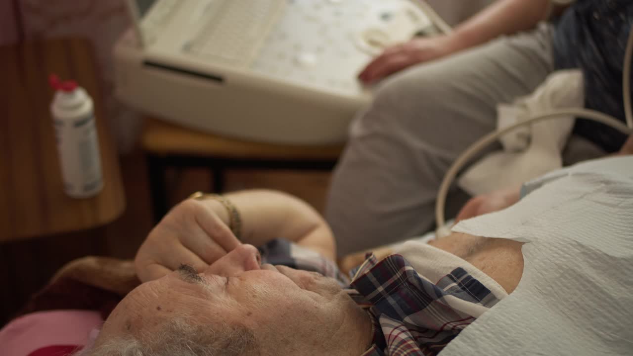 护士——医疗技术人员在家中使用便携式超声波机为97岁的老年男性患者进行超声波心脏健康检查和诊断。视频素材