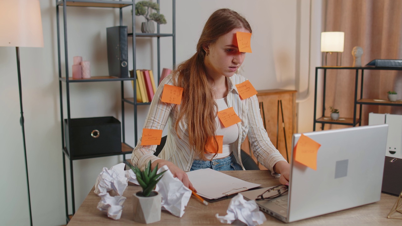 精疲力竭的女自由职业者，贴着贴纸，在办公室里用笔记本电脑，注意力不集中视频下载