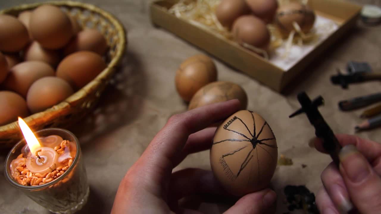 女性手拿鸡蛋，画白色花。准备绘画乌克兰复活节彩蛋装饰民间设计使用蜡抵抗的方法。复活节彩蛋视频下载