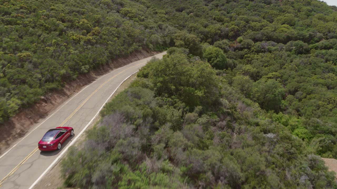 WS HA空中红色特斯拉Model S行驶在沿海山区。视频素材