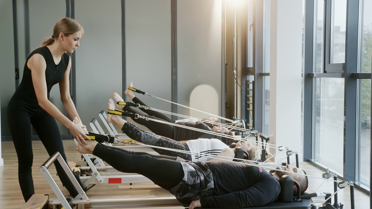 2020年11月11日，乌克兰特诺皮尔:在一名女教练的指导下，一群不同性别和年龄的人在普拉提工作室的模拟器上进行身体伸展和腿部和背部肌肉的训练视频素材