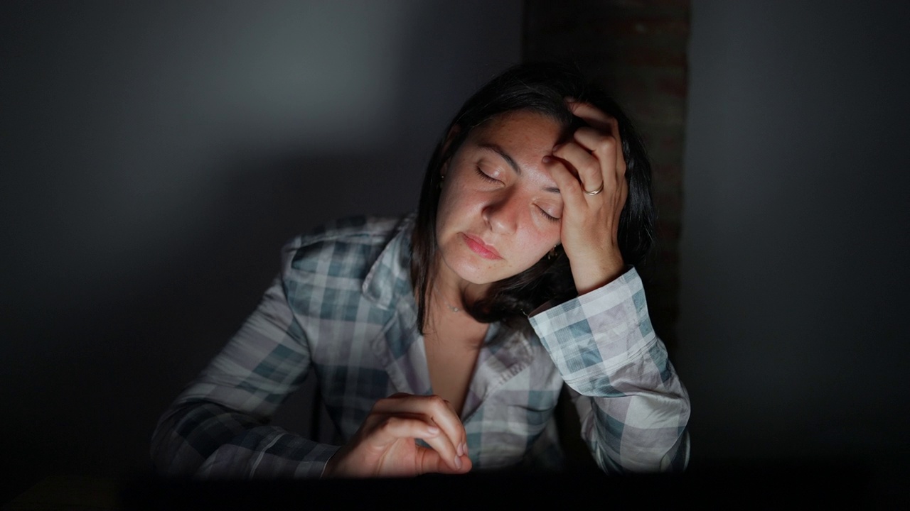 疲惫的女人晚上独自坐在电脑屏幕前视频下载