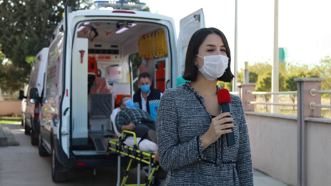 戴着口罩的新闻播音员报道了大流行期间医院前的突发新闻视频下载