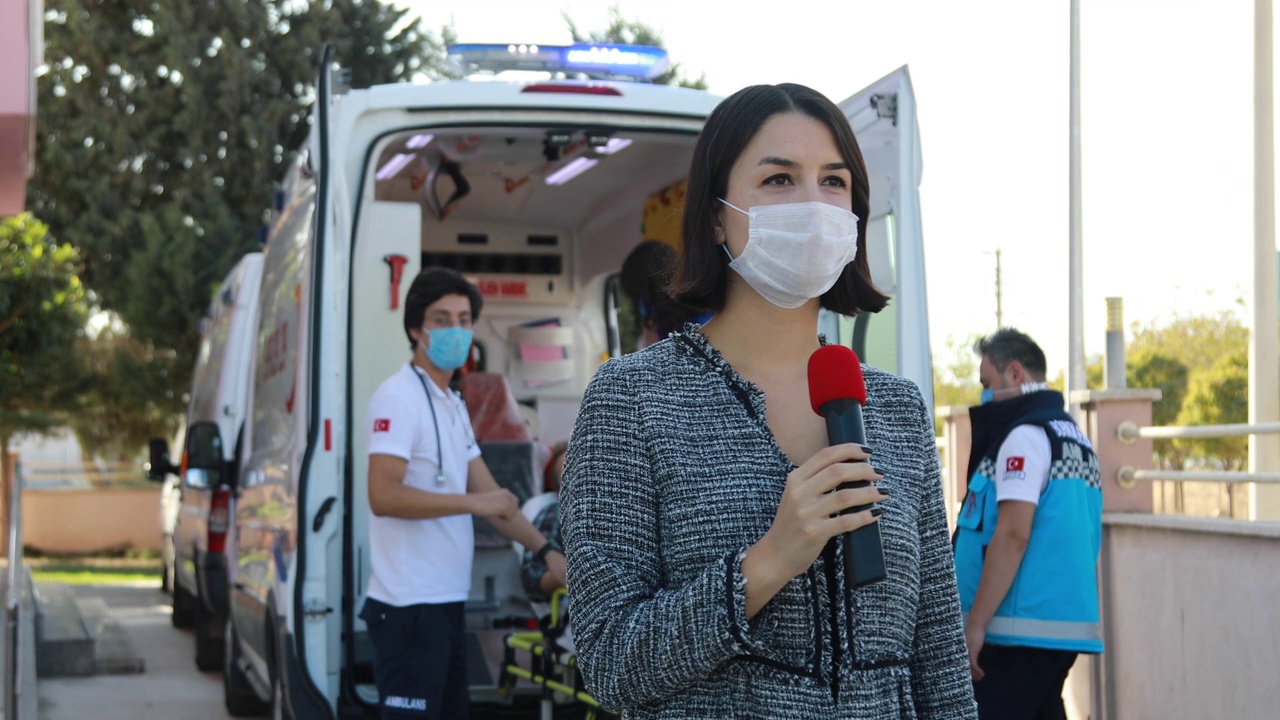 戴着口罩的新闻播音员报道了大流行期间医院前的突发新闻视频下载