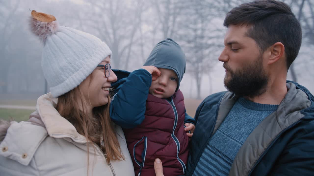父母带着儿子微笑着站在浓雾笼罩的公园里视频素材