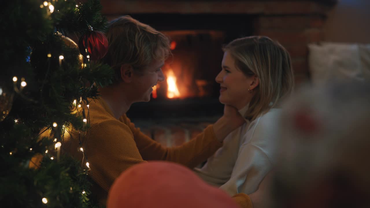一对年轻的夫妇在家里的壁炉前庆祝一个浪漫的圣诞节视频素材