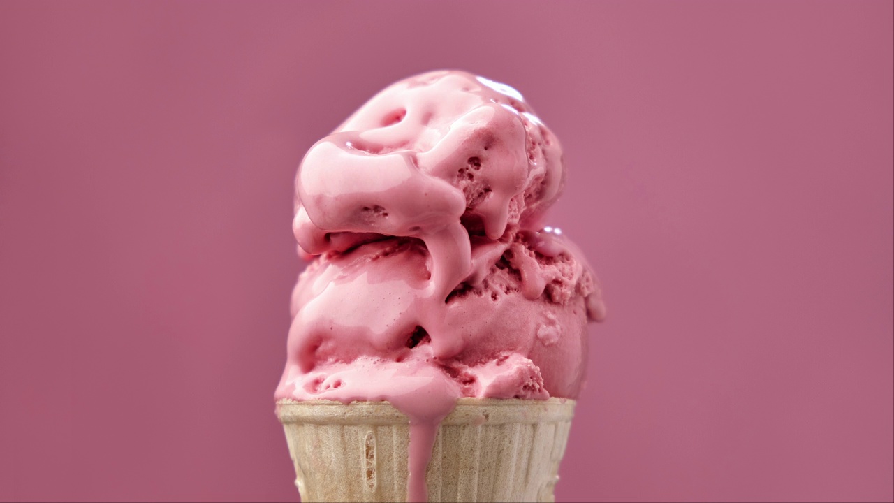 草莓冰淇淋在粉红色的背景上融化。冰淇淋融化的时间。视频素材