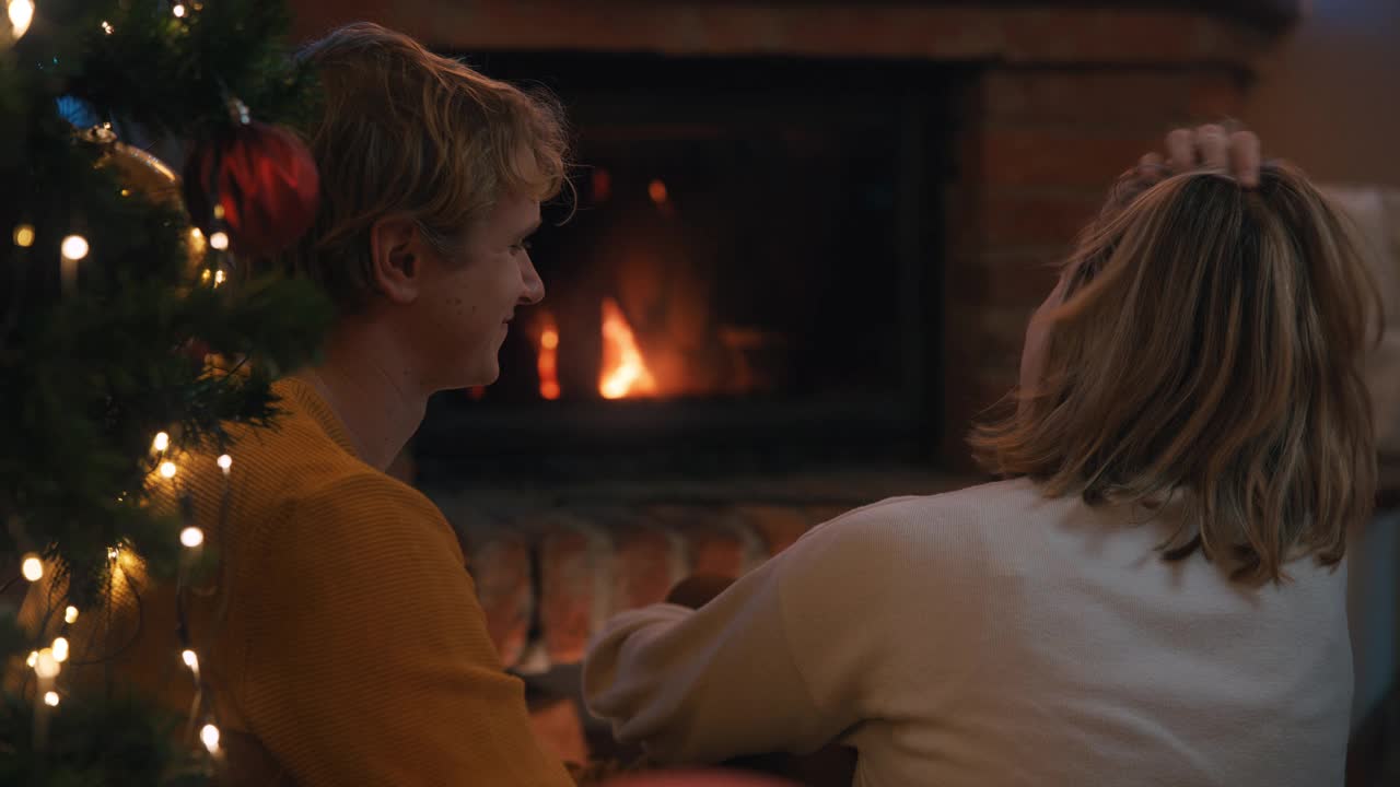 圣诞假期，一对年轻的夫妇坐在壁炉前拥抱视频素材