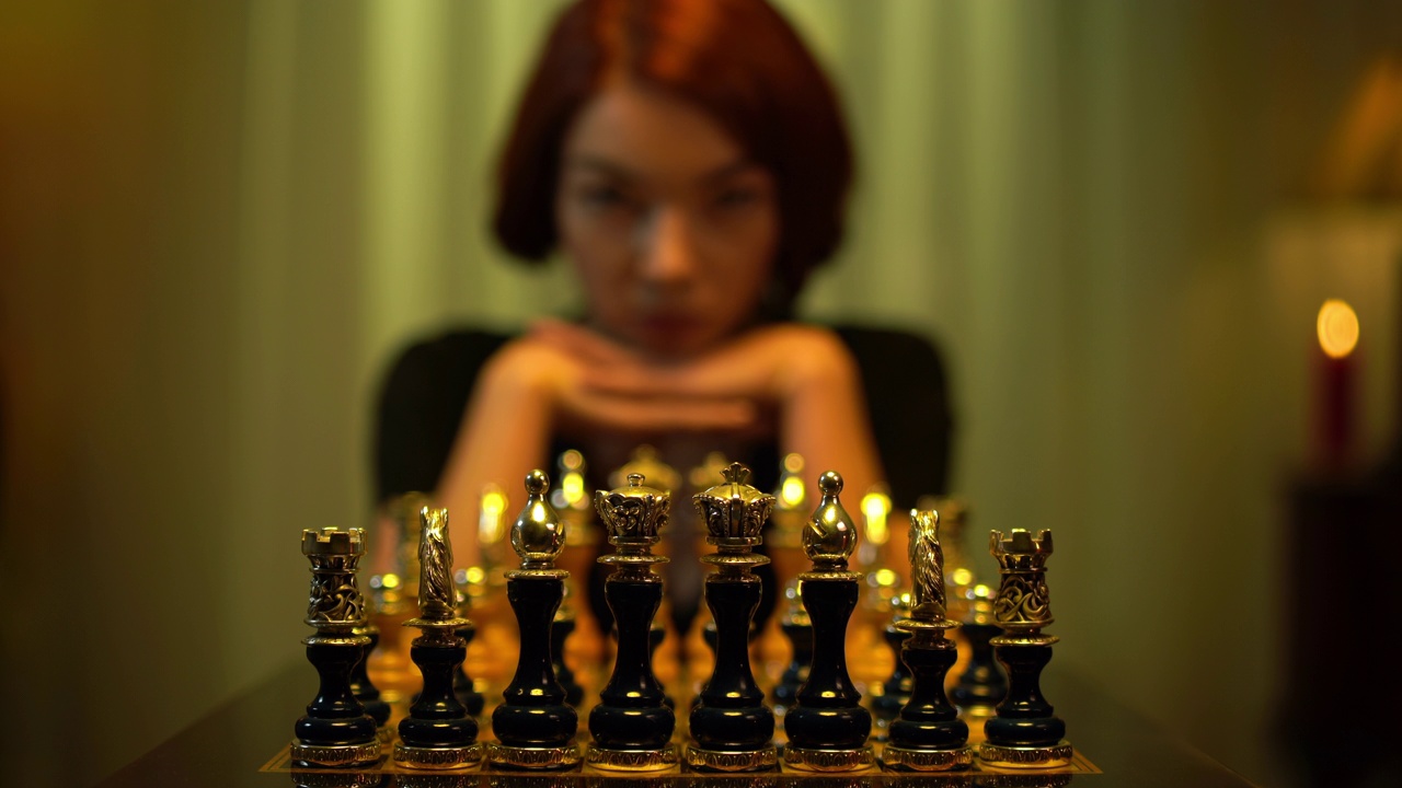 模糊的红发女棋手移动棋子思考坐在室内与棋盘。苗条的年轻白人女子在室内玩棋盘游戏。浓度和生活方式。视频下载