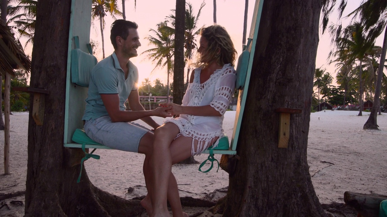 一对幸福的夫妇在日落时分的海滩上聊天。视频下载