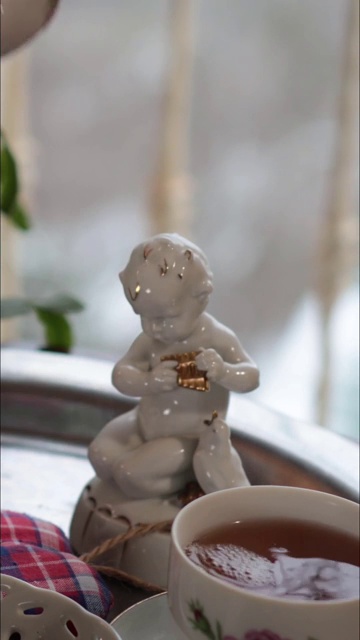 白瓷天使雕像和手从华丽的茶壶倒茶到茶杯视频下载
