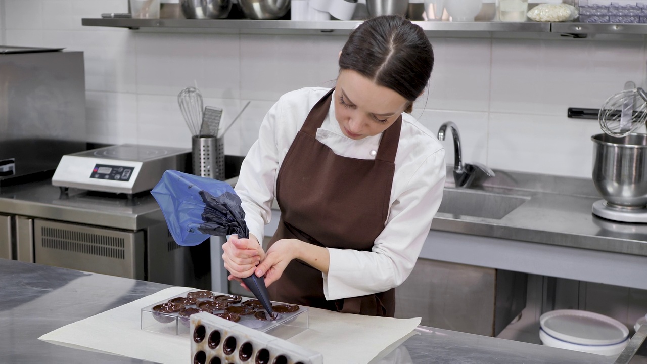Chocolatier将巧克力倒入模具。糕点袋厨师将热融化的巧克力填入硅胶模具视频素材