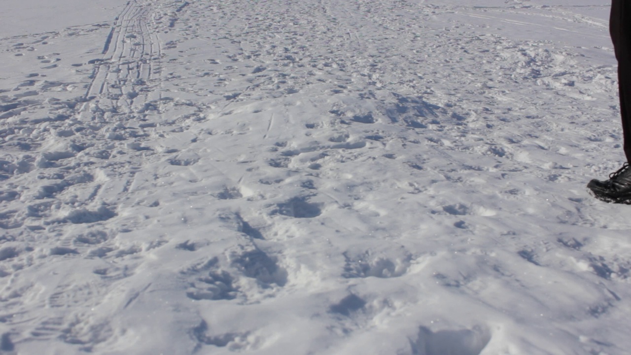 一个男人在冬天的雪地里行走。走在冬天。沿着下雪的路走。视频下载