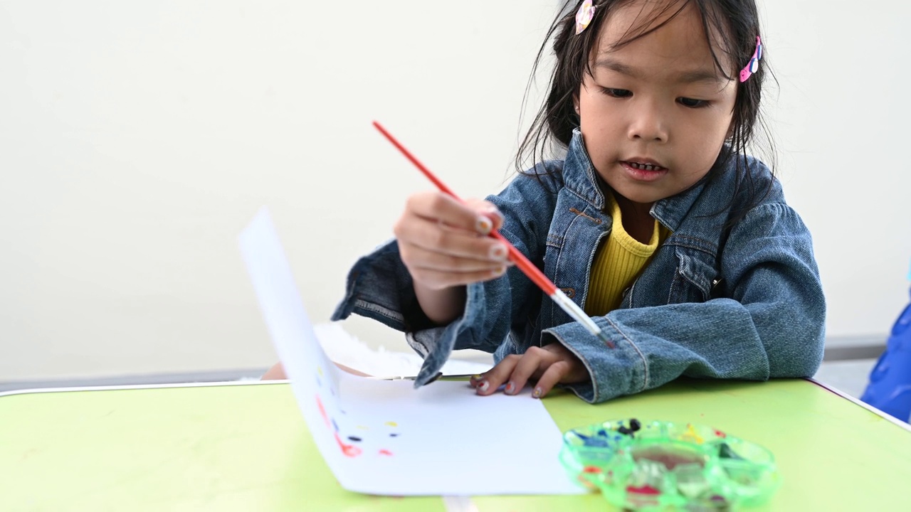 亚洲女孩有乐趣绘画和绘画在家里。视频素材