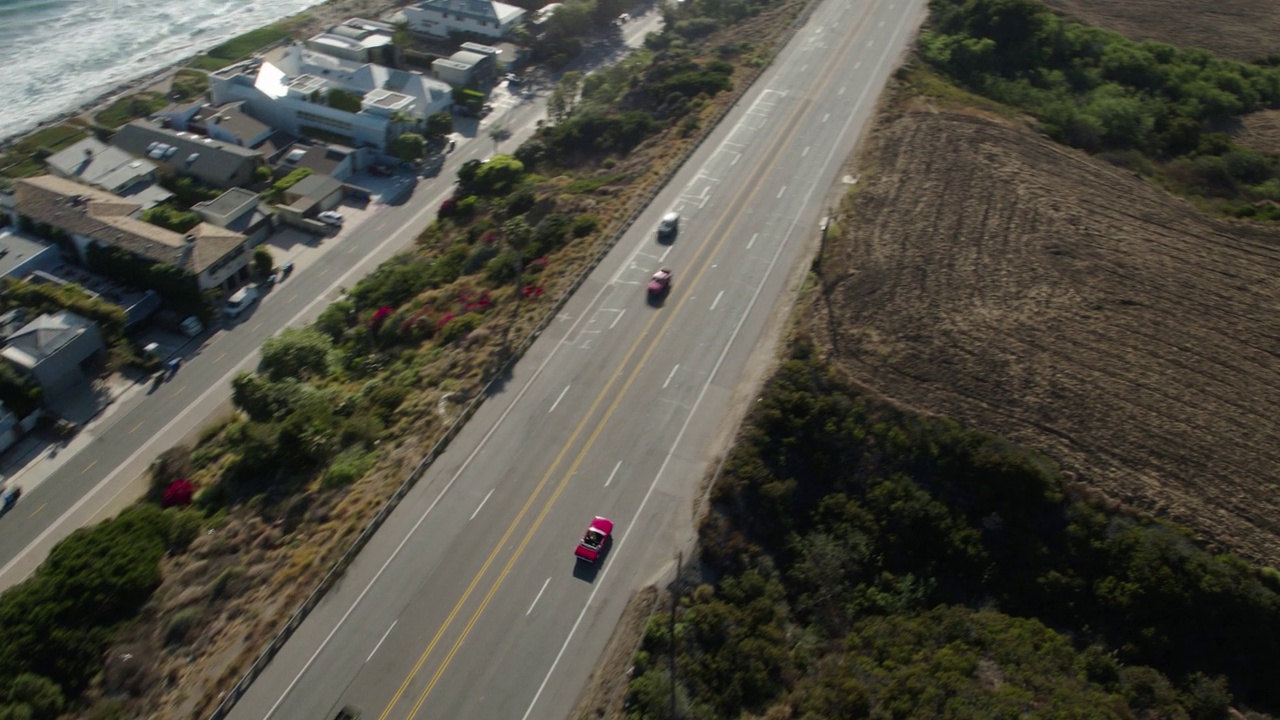 加州马里布，阳光明媚的一天，一辆红色汽车在公路上行驶视频下载