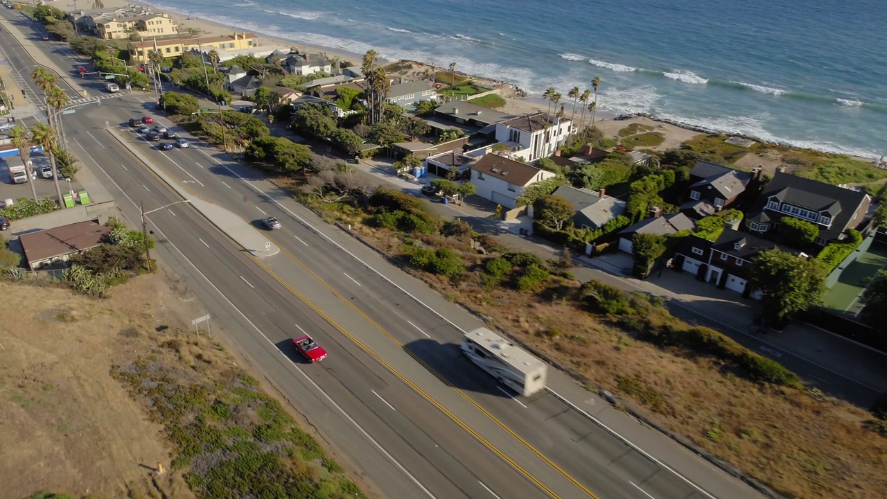 红色敞篷车在沙滩上行驶的航拍镜头，无人机向后飞行在风景上-加州马里布视频下载