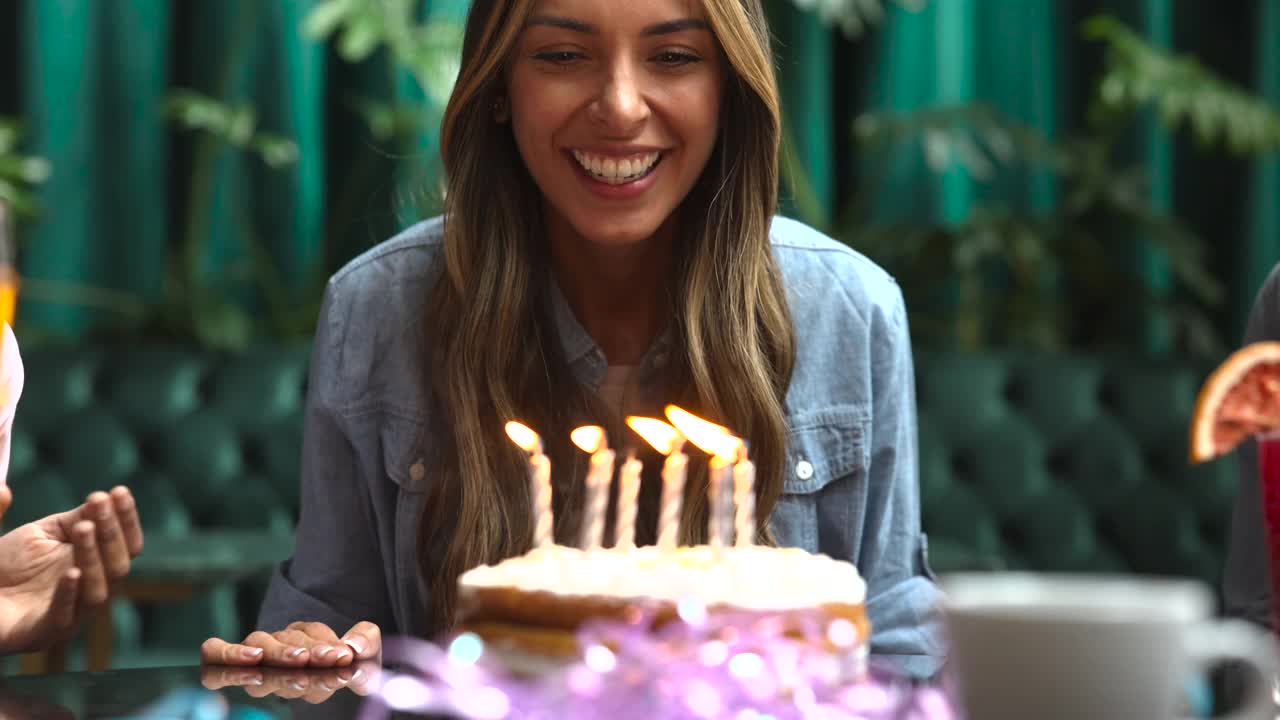 美丽的女人庆祝她的生日吹灭蛋糕上的蜡烛看起来很高兴的特写视频下载