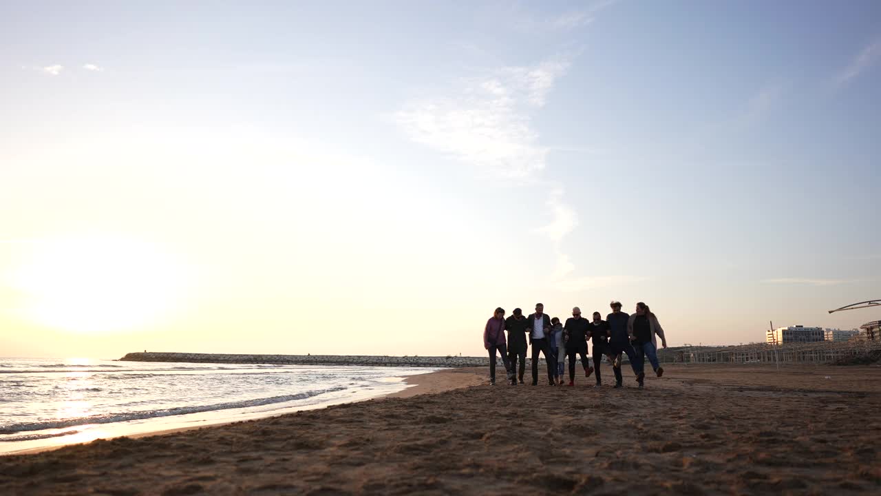 一群快乐的朋友在秋日的沙滩上跳跃。视频素材
