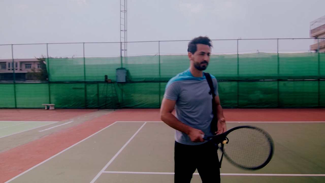 中东男子走进网球场的慢镜头。轨道。视频下载