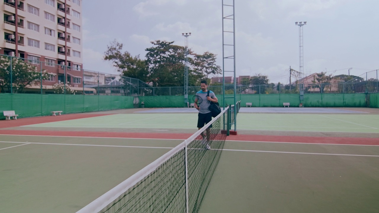 中东男子走进网球场的慢镜头。步行通过。视频下载