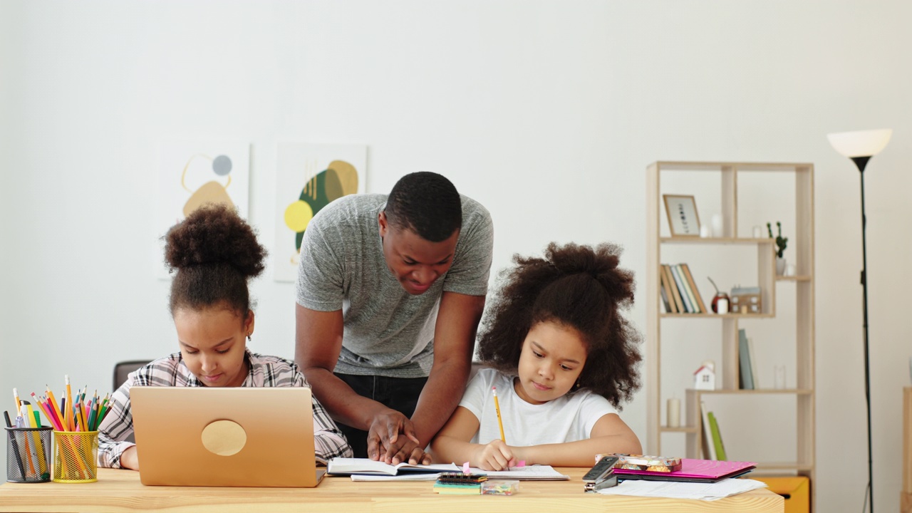 在线学习有趣的微笑积极的情绪黑人家庭非洲裔美国父亲在家教课，他的女儿们坐在桌子和笔记本电脑前视频下载