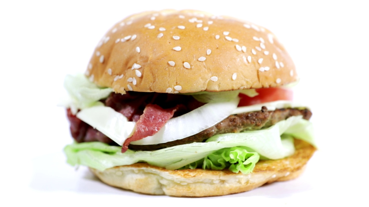 一个美味新鲜的自制汉堡在桌子上旋转的特写，孤立在白色背景上视频下载