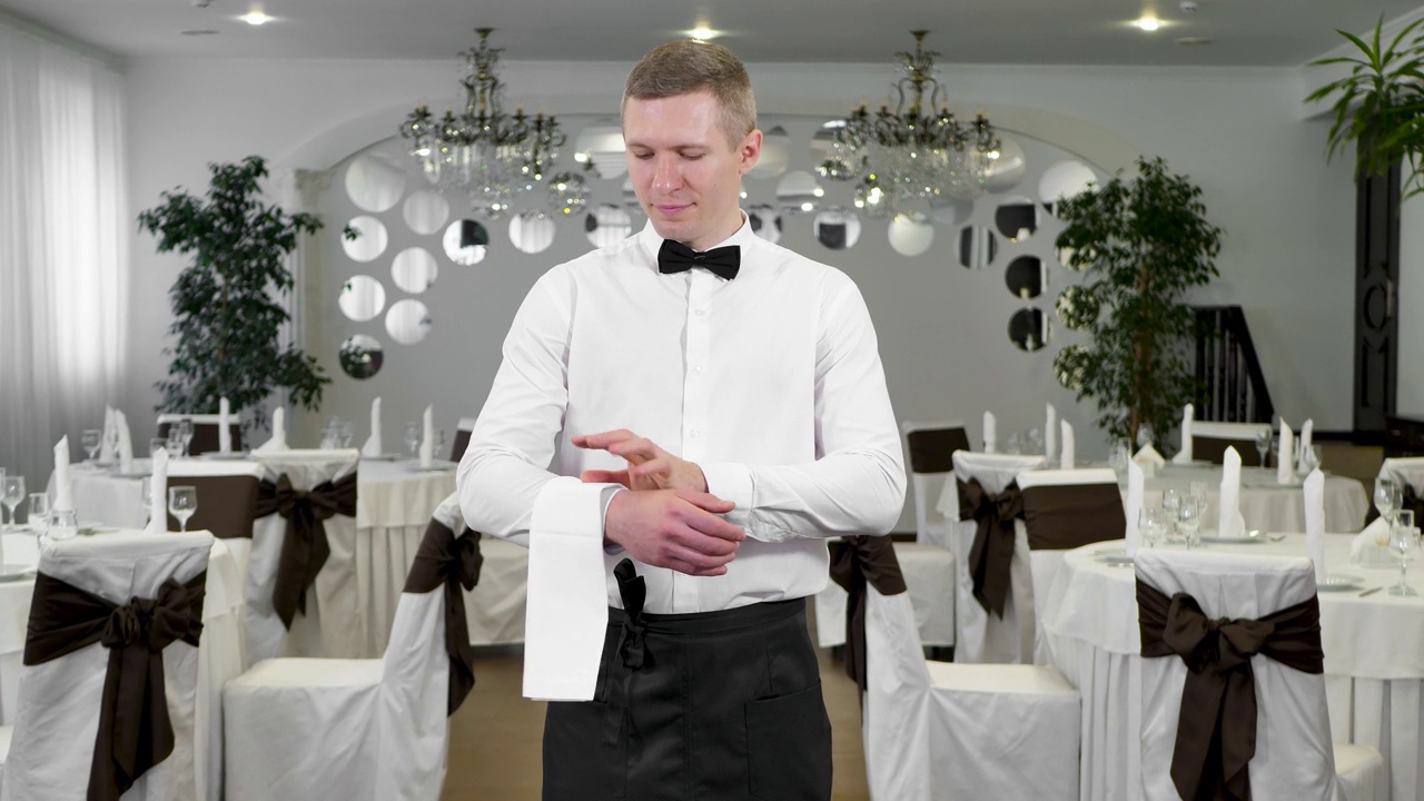 一个穿着经典制服的男服务员把一条白毛巾放在手上视频下载