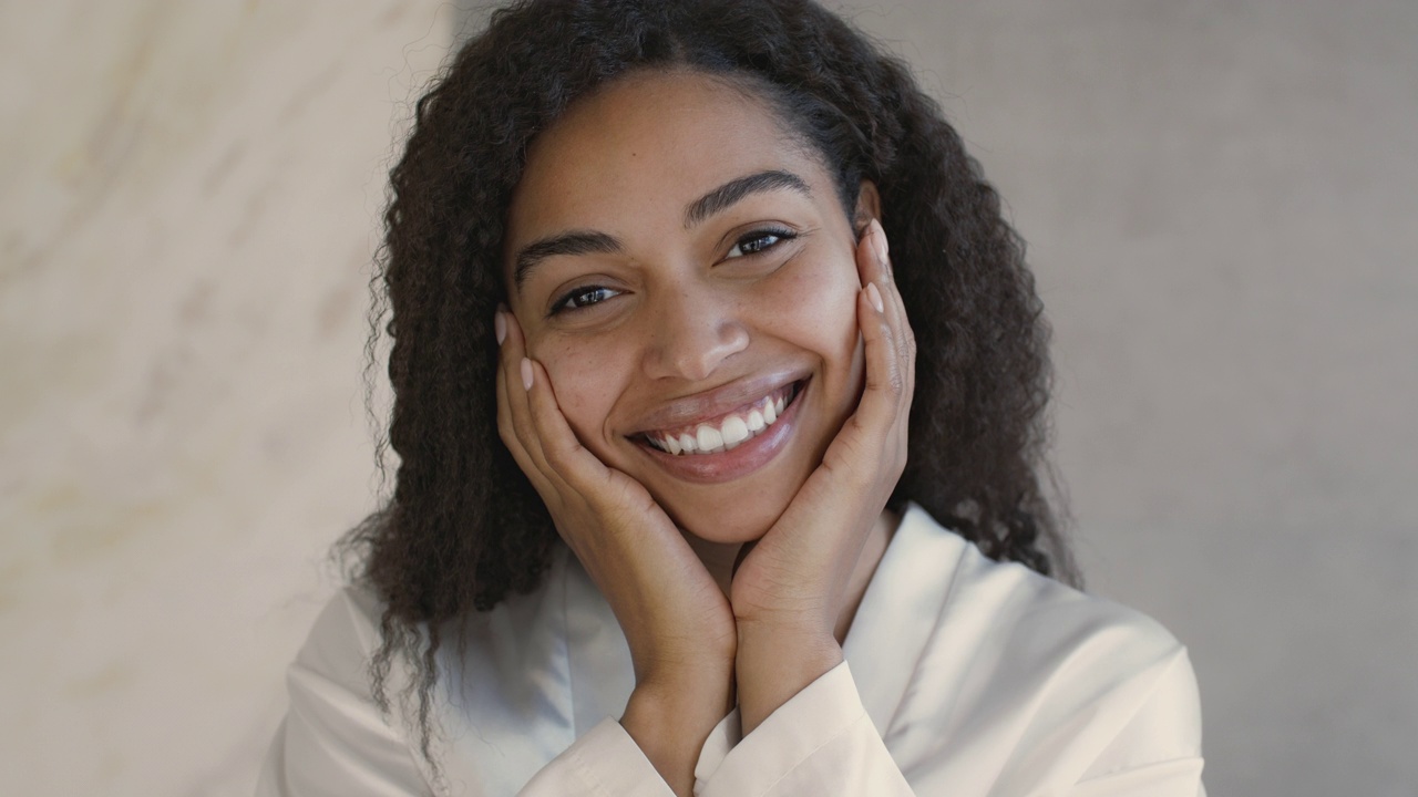 自然美景的概念。年轻的积极的非洲裔美国妇女的特写镜头微笑着，触摸她光滑的脸颊视频下载