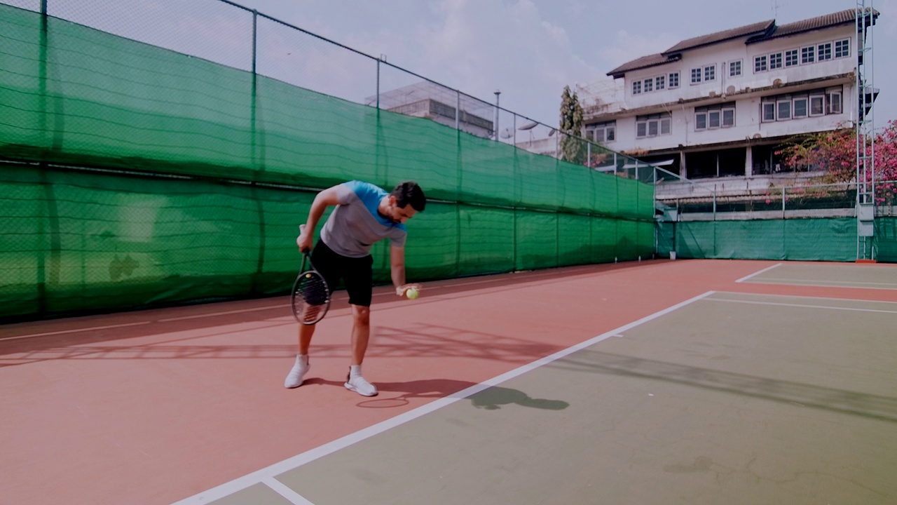 一名中东男子准备在网球场上发球的慢镜头。行走轨道视频下载