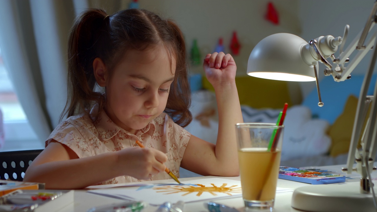 学前班的小女孩在家里的桌子上用水彩画作画。视频下载