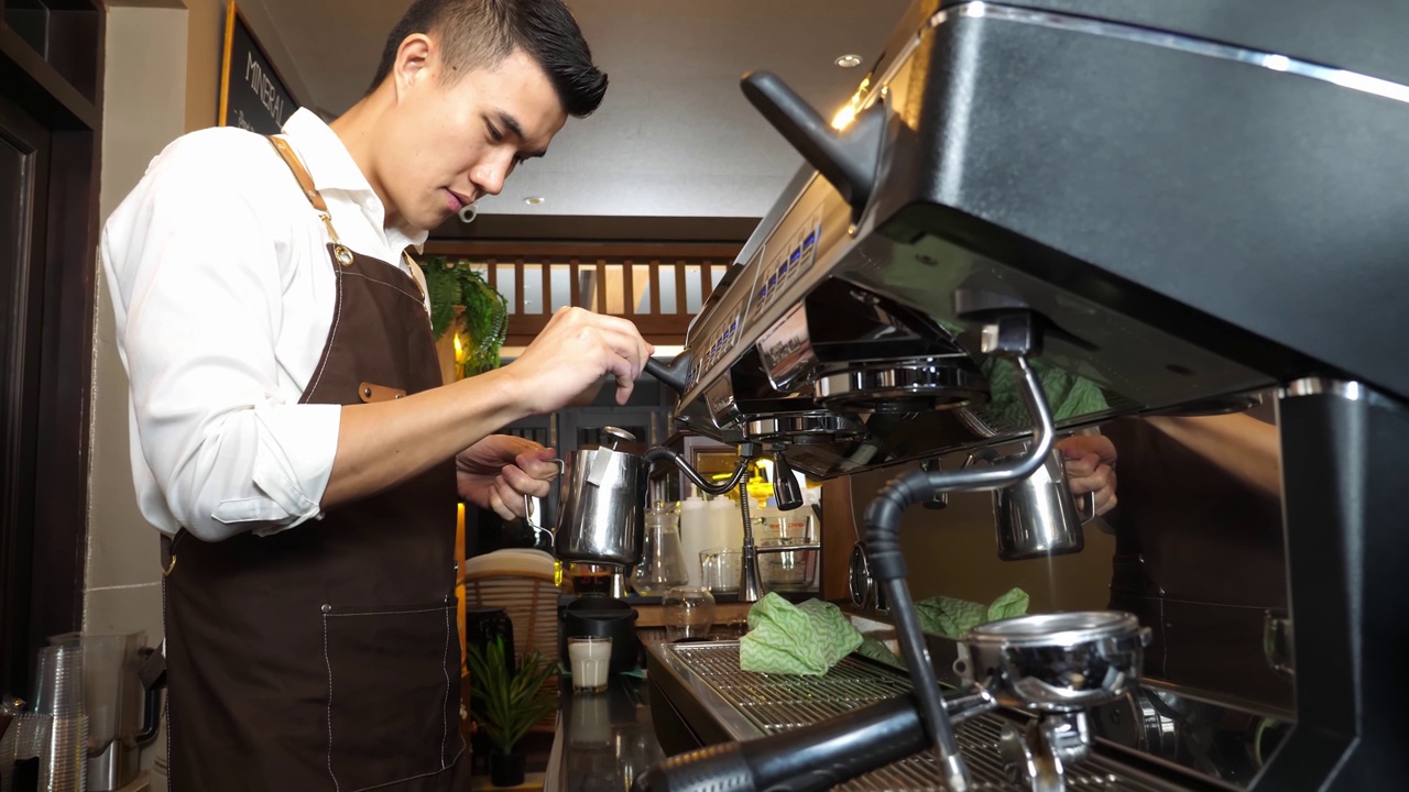 男子咖啡师使用咖啡机流牛奶为特殊的饮料在咖啡馆咖啡馆视频下载
